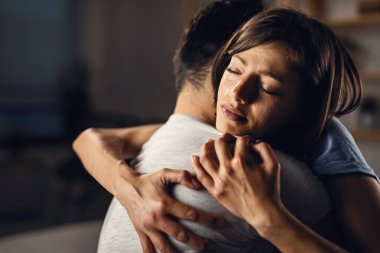 Young crying woman seeking for solace and embracing her boyfriend with eyes closed. 