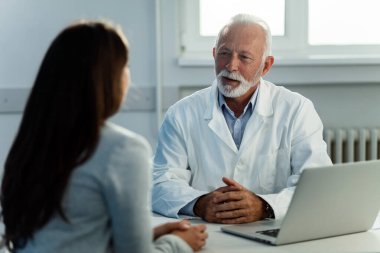 Senior doctor talking to female patient during medical consultations at doctor's office. 