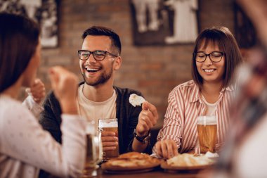 Happy couple enjoying with friends while drinking beer and communicating  in a tavern. 
