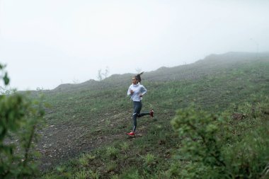 Above view of determined young athlete running along the cliff in nature during foggy weather. Copy space.
