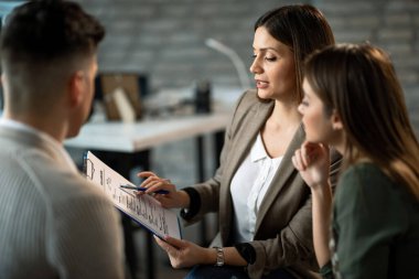 Young financial advisor talking to a couple while making plans about their future investments during a meeting in the office. 