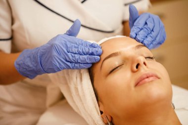 Close-up of young woman enjoying in facial massage at beauty salon. 
