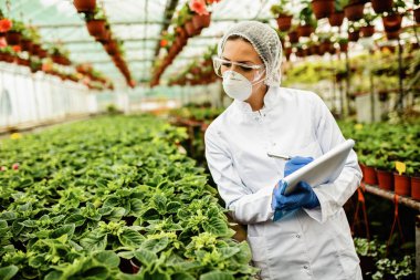 Female scientist writing report during quality control inspection in a plant nursery. 