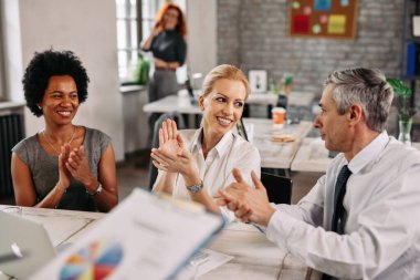 Group of happy business colleagues clapping hands after attending an presentation in the office. 