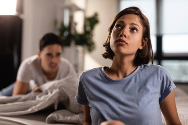 Young woman paying no attention to her boyfriend and ignoring him while he is trying to talk with her after the fight. 