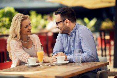 Happy man enjoying in conversation with his girlfriend while being on a date in a cafe. 