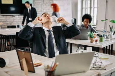 Businessman punching the air and looking up while celebrating success in the office. 