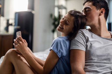 Young woman feeling happy while spending time with her boyfriend who is kissing her. 