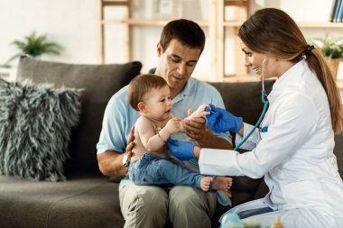 Happy female doctor listening small boy's heartbeat with a stethoscope during medical appointment. 