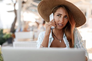 Young Beautiful woman sitting in a cafe and communicating on cell phone while thinking of something. 