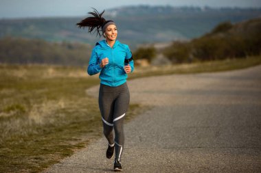 Dedicated female runner jogging in nature at dawn. Copy space.
