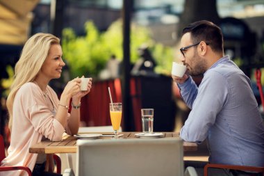 Happy couple communicating while relaxing in a cafe and drinking coffee. 