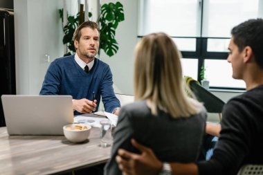 Financial consultant communicating with a couple while going through their home finances. 
