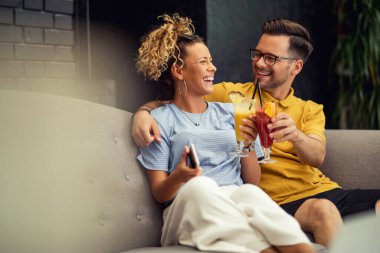 Young couple in love having fun while toasting with cocktails and celebrating in a cafe. 