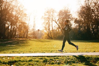 Full length of black sportswoman jogging in nature. Copy space. 