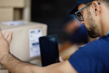 Close-up of courier using digital tablet and scanning bar code on a delivery box. 