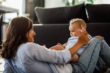 Happy mother spending time with her baby boy at home. 