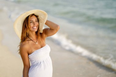 Young happy woman in summer dress spending her day by the sea. 