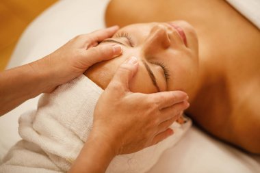Close-up of young woman enjoying in head massage during beauty treatment at the spa. 