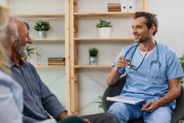 Happy healthcare worker visiting senior patients at home and communicating with them 