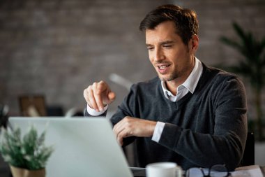 Happy male entrepreneur working on a computer while sitting at his desk in the office. 
