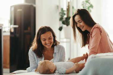 Two happy woman and their baby enjoying in the time together at home. 