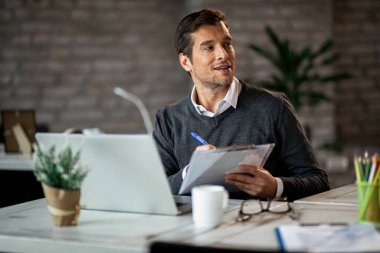 Businessman writing notes while working on reports and finishing paperwork in the office. 