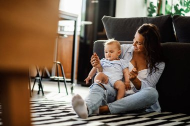 Happy mother enjoying in time she is spending with her baby boy at home.