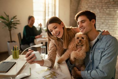 Ofiste bir köpekle selfie çekerken cep telefonu kullanan mutlu bağımsızlar.. 
