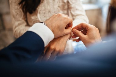 Close up of groom giving his bride bracelet as symbol of his love on their wedding day. 