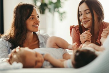 Young happy mothers talking while spending time with their babies at home. 