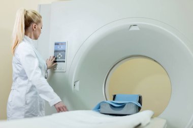 Female doctor adjusting MRI scanner before medical examination at clinic. 