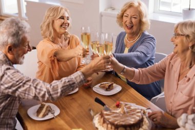 Group of cheerful senior people raising a glass and toasting on a Birthday party at home. 