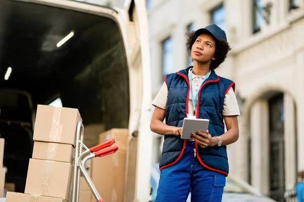 Black Female Courier Using Digital Tablet While Unloading Packages Delivery — Stockfoto