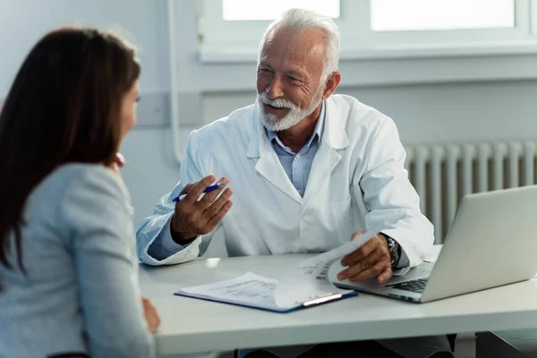 Happy Senior Doctor Filling Medical Records While Communicating Female Patient — Stockfoto