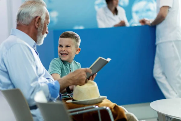 Happy Little Boy His Grandfather Reading Book Communicating While Waiting — Stockfoto
