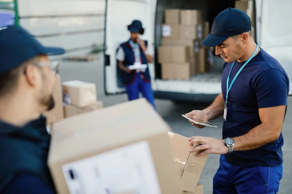 Young Delivery Man Using Touchpad Checking Packages While Organizing Delivery — Stock Fotó