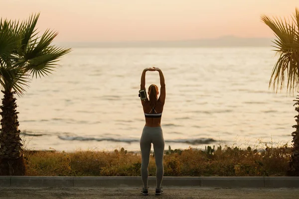 Back View Sportswoman Doing Stretching Exercises Sunrise Sea Copy Space — ストック写真