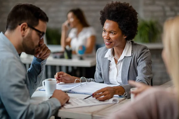 Black Smiling Insurance Agent Talking Client While Going Paperwork Meeting — Stock Fotó