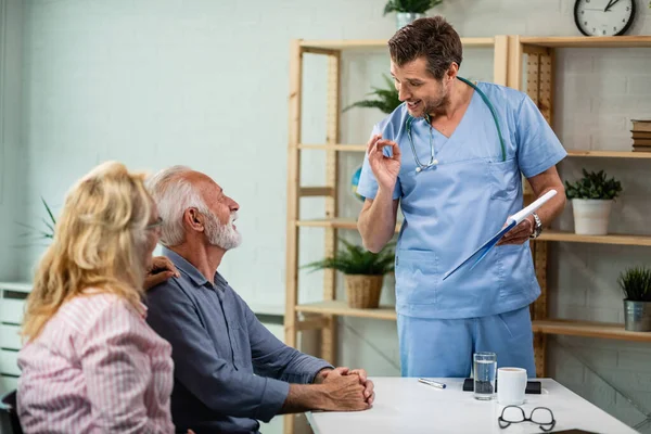 Happy doctor feeling satisfied while talking with senior couple about their medical reports. 