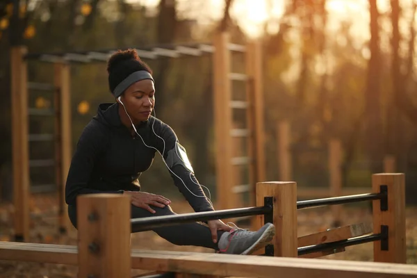 Black female athlete warming up and doing stretching exercises in nature.