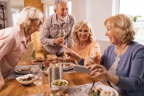 Group Happy Senior Friends Using Mobile Phone Communicating While Having — Foto Stock