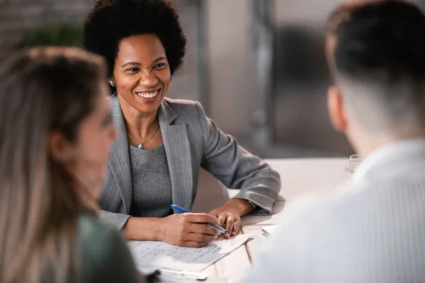 Happy African American financial advisor giving consultations to a couple while making their future investment plans. 