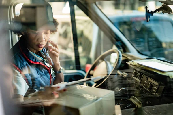 Black Delivery Woman Reading Distribution List While Talking Cell Phone — Stockfoto