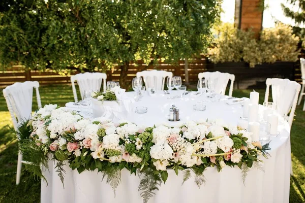 Elegant table setting with floral arrangement at outdoor wedding reception.