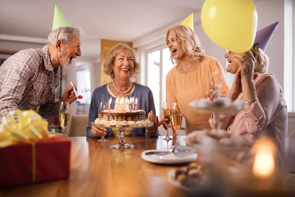 Group of cheerful senior people singing while celebrating woman\'s Birthday  at home.