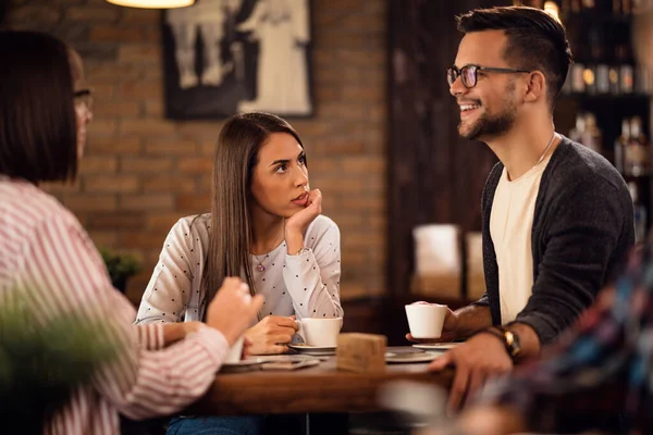 Young woman and her friends drinking coffee and communicating in coffee shop. 