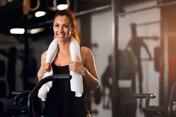 Happy athletic woman with towel around her neck taking a break while having spinning class in a gym. Copy space.