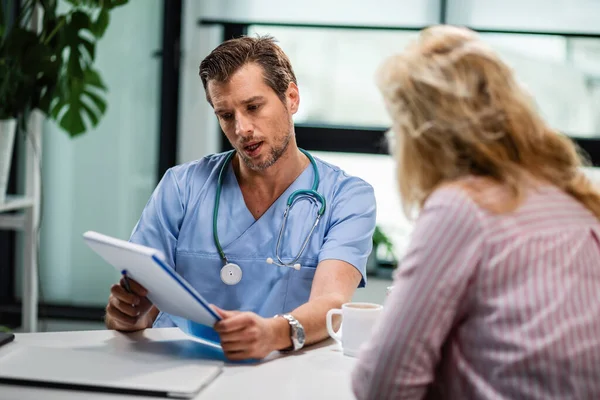 Male Doctor Reading Medical Reports While Talking His Female Patient — Foto de Stock