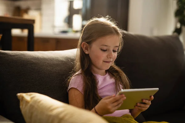 Happy Little Girl Reading While Using Digital Tablet Sofa Living — Stockfoto